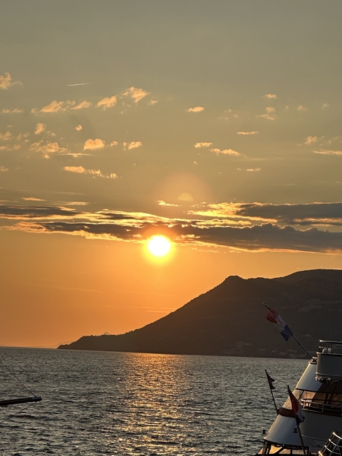Golden sunset with clouds, a mountain peak in the foreground.