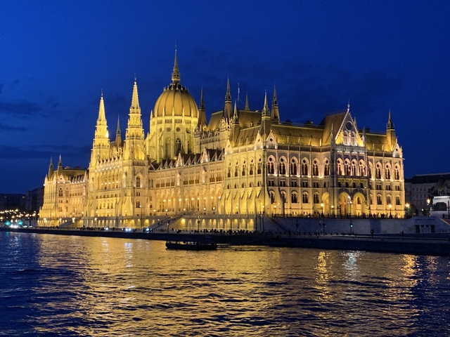       Illuminated parliament building at night, reflecting on water.
  