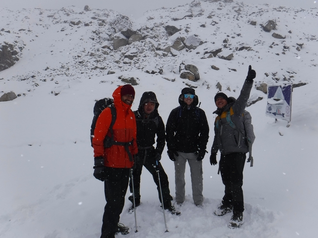 Group of people in winter clothing standing in a snowy landscape.