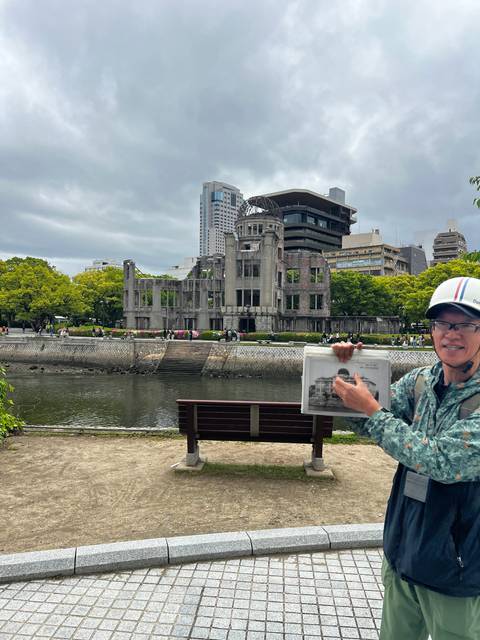       Historical building with a person holding a black-and-white photo.
  