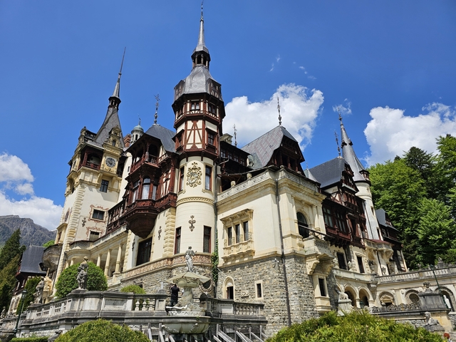 Peleș Castle with rich architectural details under a blue sky.