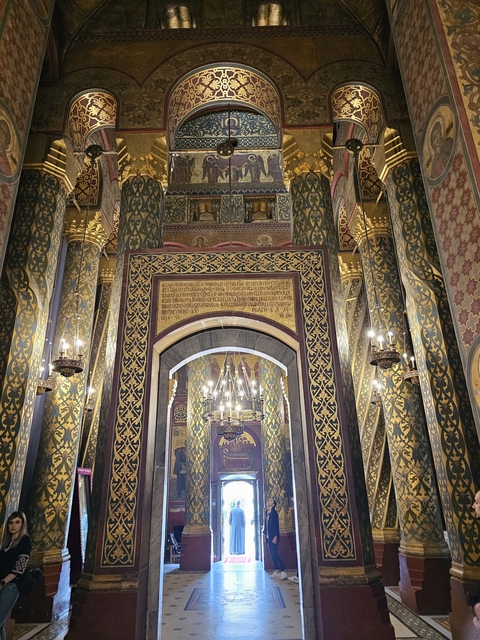 Interior of an ornate church with golden decor and chandeliers.