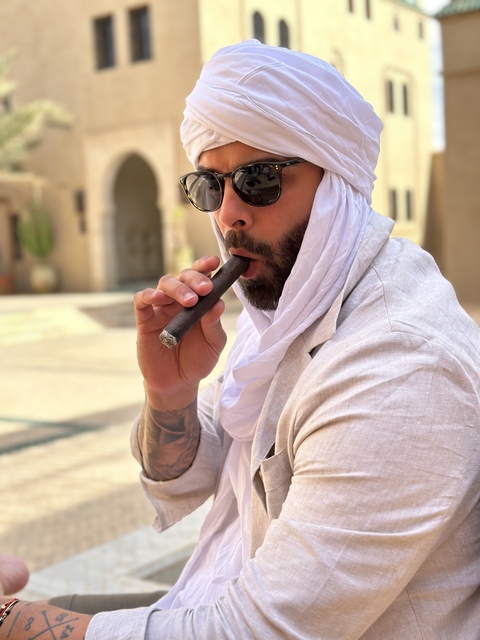 Man in traditional outfit smoking a cigar.