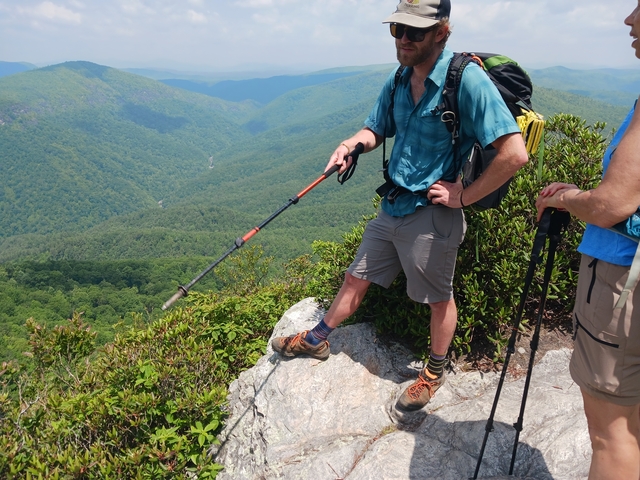 Hikers standing at the edge of a mountain with trekking poles.