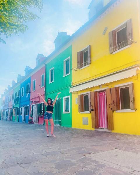 A woman posing in front of colorful buildings.