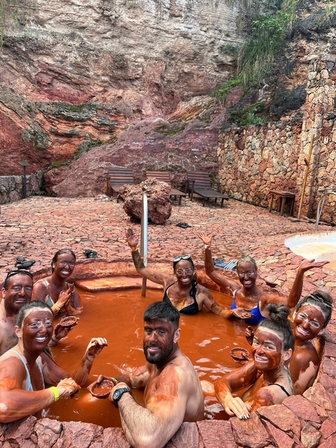Group of people covered in mud in a natural setting.
