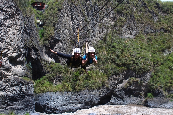 Two people ziplining over a canyon.