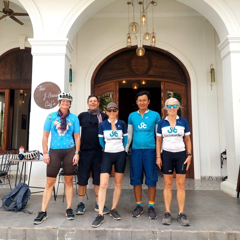 People in cycling jerseys posing in front of a building