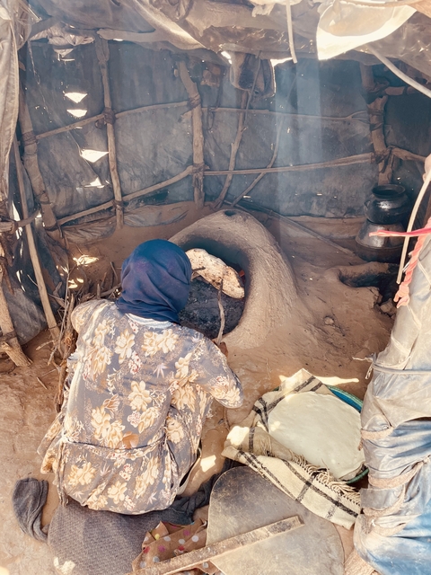 Person working with a clay oven, baking.