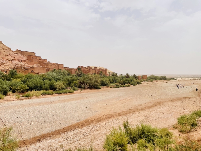       Traditional Moroccan town with a riverbed and lush foliage.
  