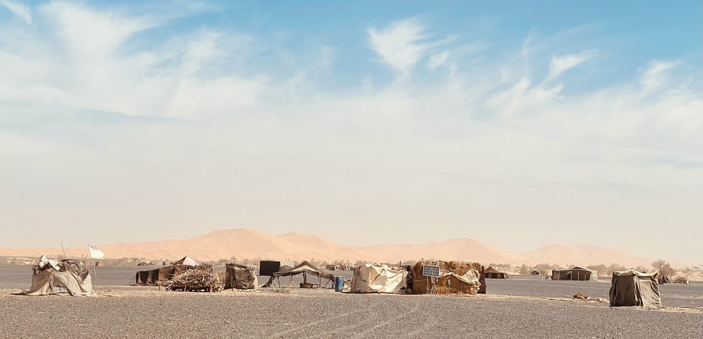 Desert encampment with tents under a bright sky.