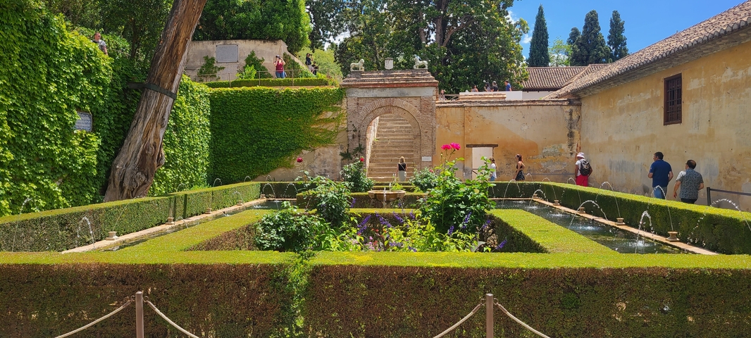       Beautiful garden with symmetrical hedges and a stone archway.
  