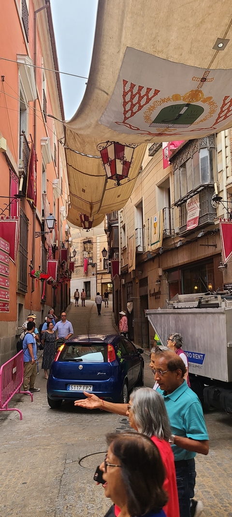       Narrow street with vibrant banners and historic architecture.
  