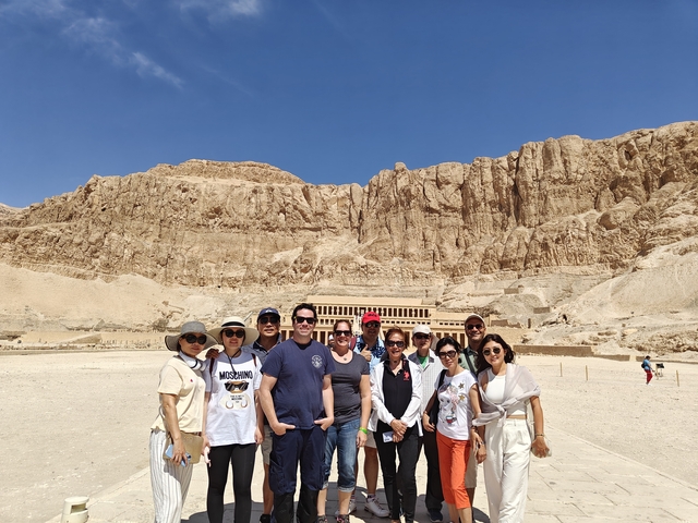 Group of people posing in front of a historical site in the desert.