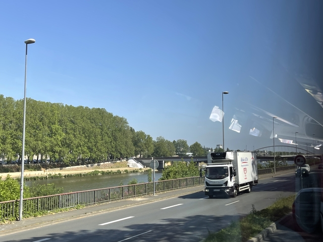 Roadside view with a truck and greenery, taken from a bus.