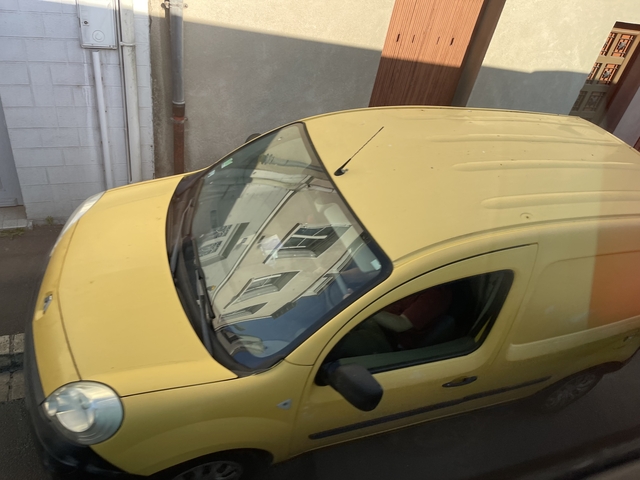 Yellow van parked along a narrow street.