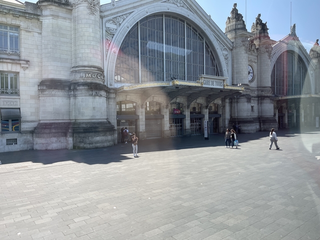 People walking in front of a historic railway station.