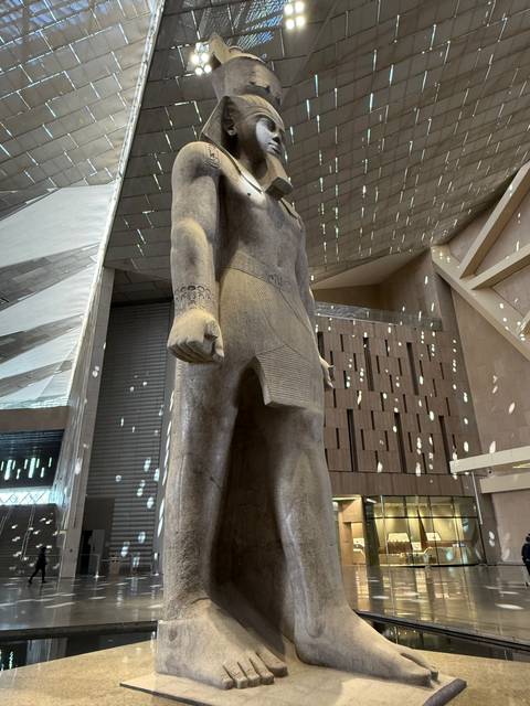 A large statue of an ancient Egyptian figure inside a museum.