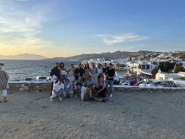 Group photo with a scenic coastal backdrop and white buildings.