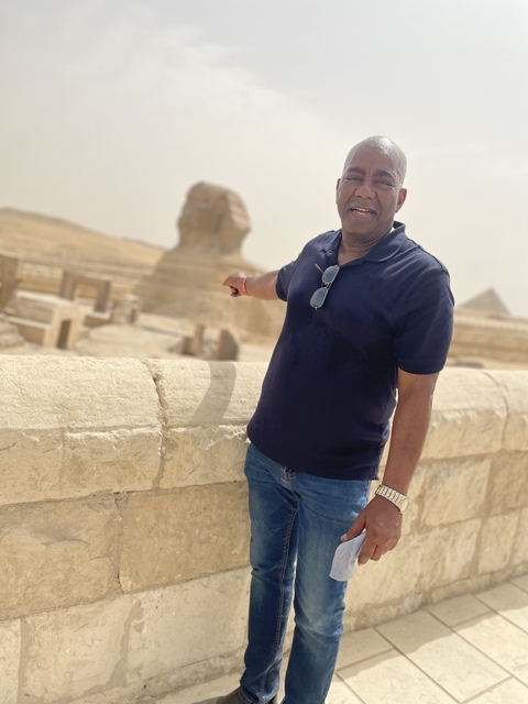       Person posing with the Sphinx and Pyramid in the background.
  