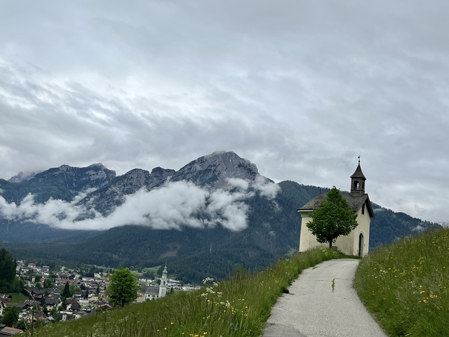A church in the foreground with mountains and clouds in the background.