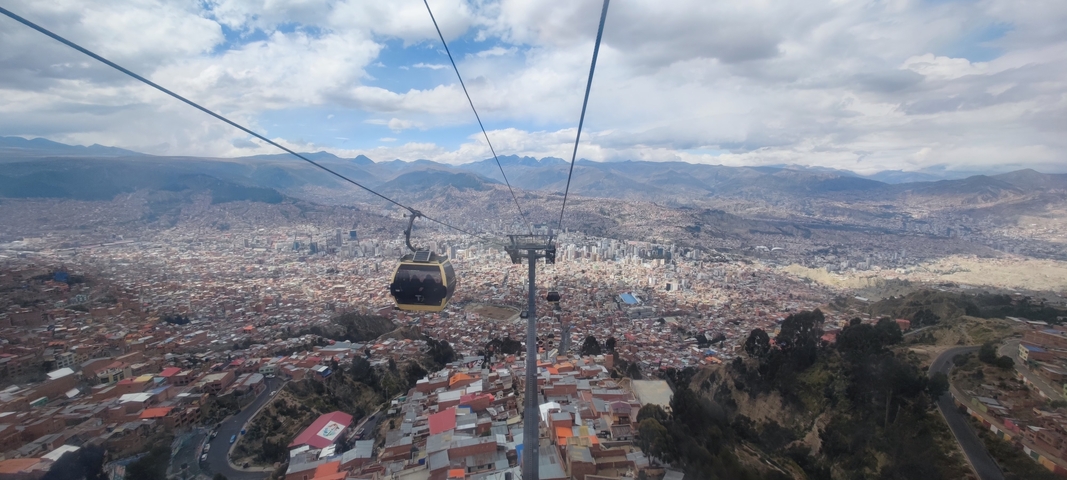 Cable car over a sprawling urban landscape with mountains.