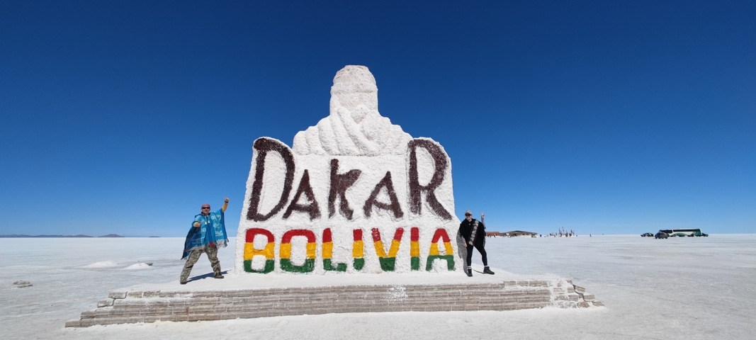 Dakar Bolivia statue in a salt flat with two people posing.