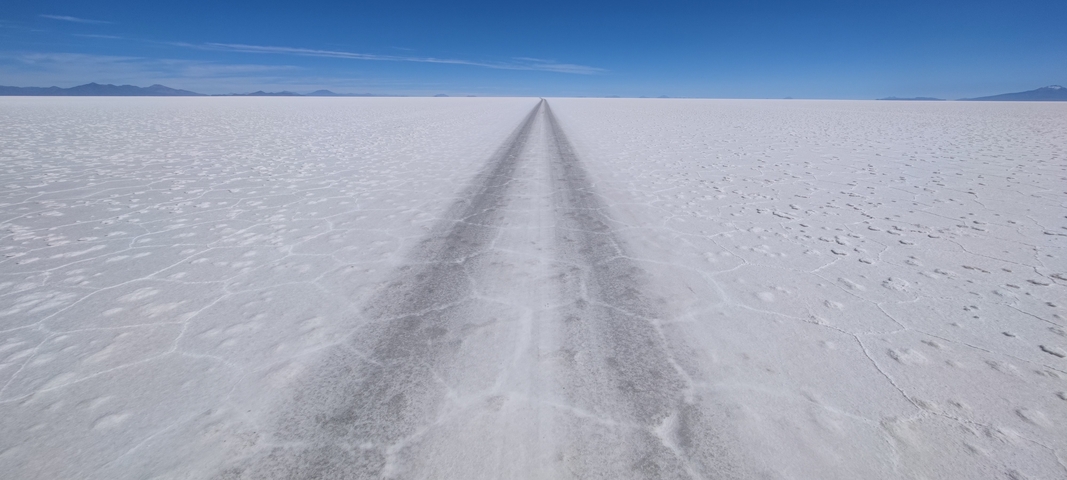       Long perspective view of a track across a vast salt flat.
  