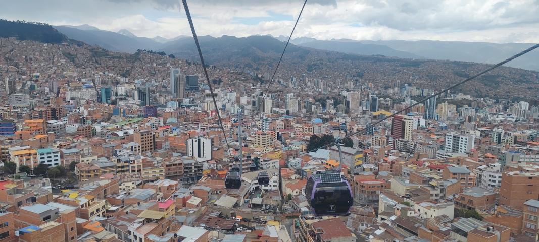 Cityscape view from a cable car over a dense urban area.