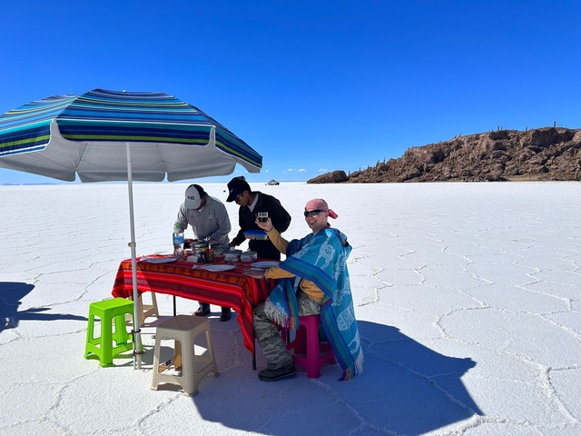       Group having a meal under an umbrella on the salt flats.
  
