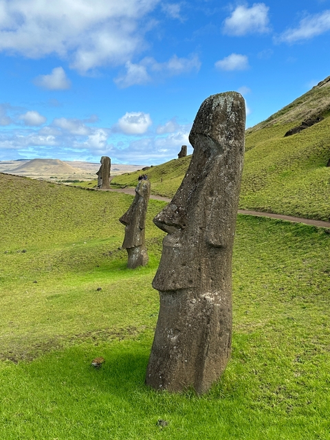 Stone statues with grassy fields and hills.