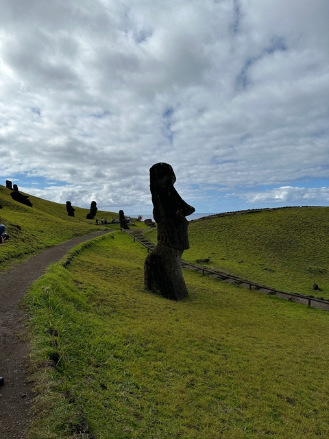 Large stone statues on a grassy hill.