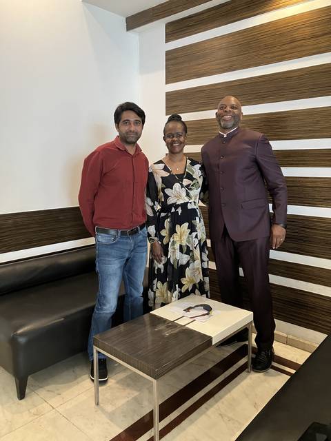 Three people posing inside a modern building.