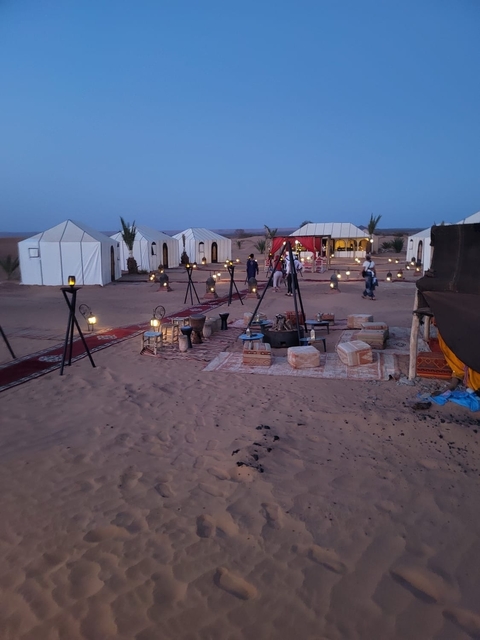       A desert camp with many tents and decorative lighting at dusk.
  