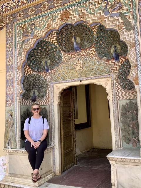 Person by ornate peacock archway in Jaipur, India.