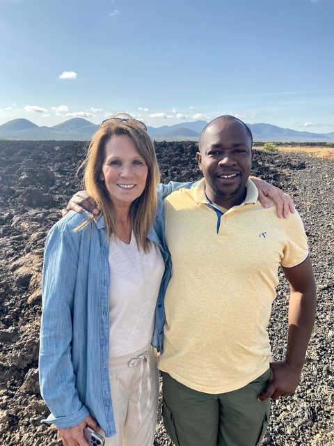       Two people smiling with rocky terrain in the background.
  
