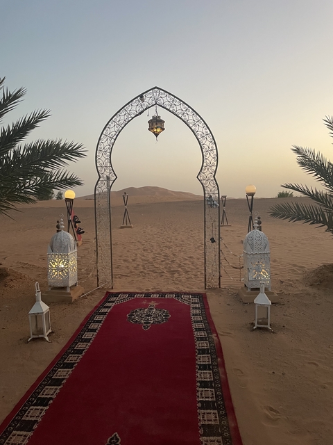       Decorative gate in a desert with lanterns.
  