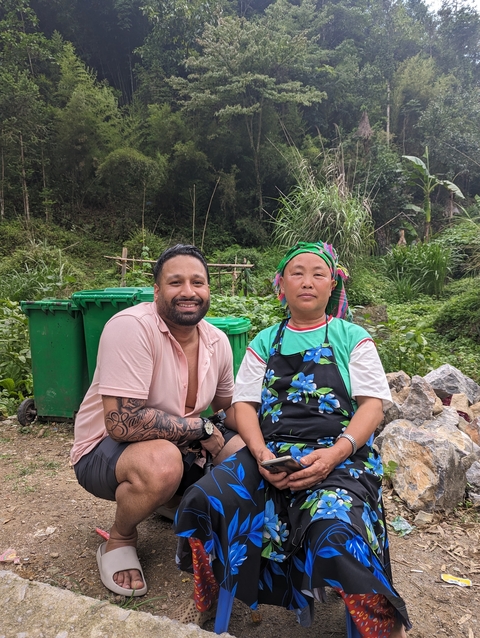       Person posing with a local, surrounded by greenery.
  