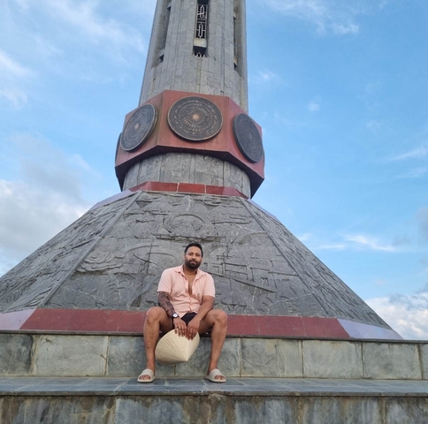 Person sitting at the base of a large monument.