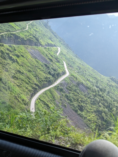       Snaking road on a lush green mountain side.
  