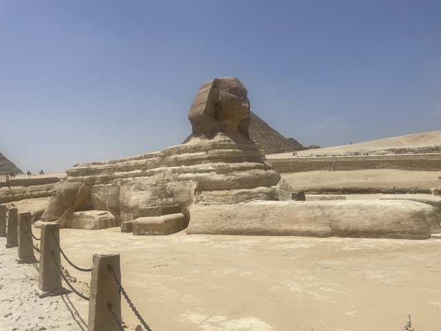       Statue of a sphinx with pyramids in the background.
  