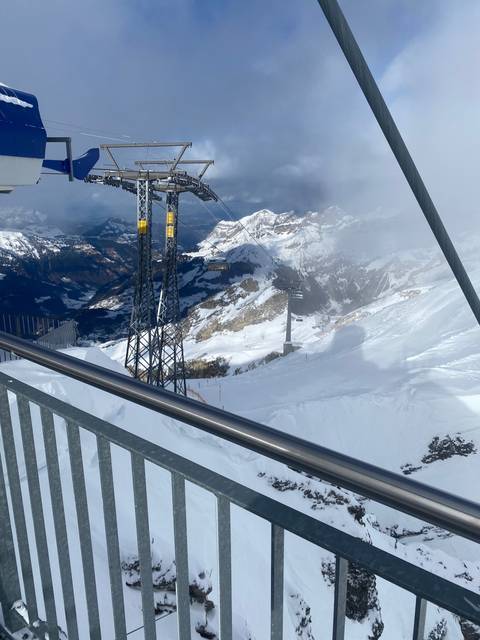 Snow-covered mountain range with ski lift and clear sky.