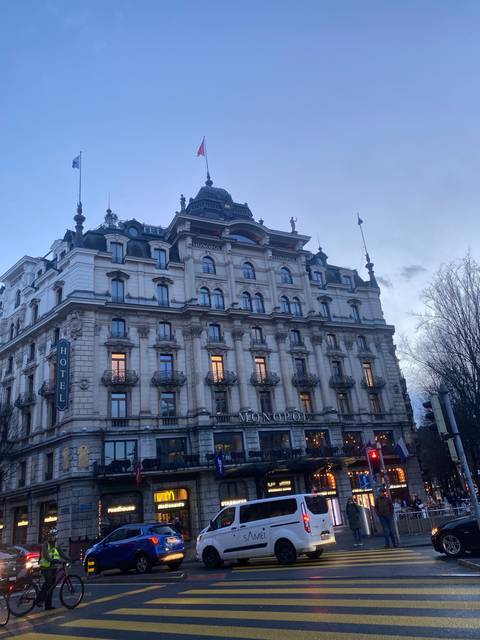 Luxurious hotel building with cars on the street.