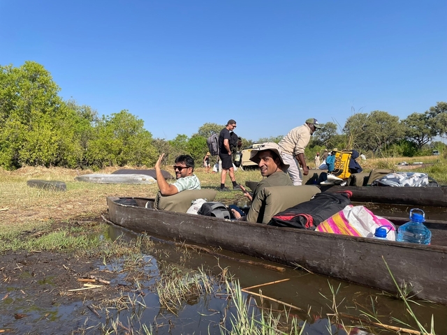 People in small boats on a calm water body in a natural setting.