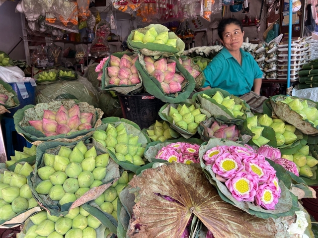 Vendor selling lotus flowers at a market.