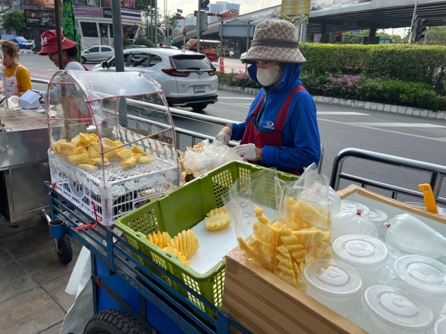 Street vendor selling cut pineapple in a city setting.