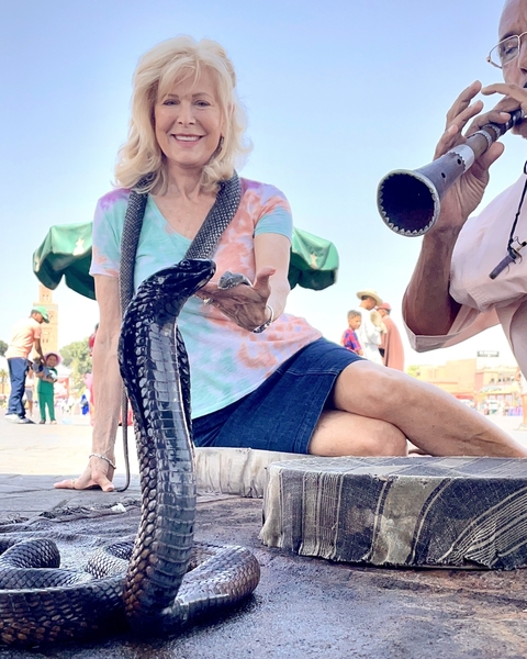       Woman interacting with a snake and a snake charmer
  