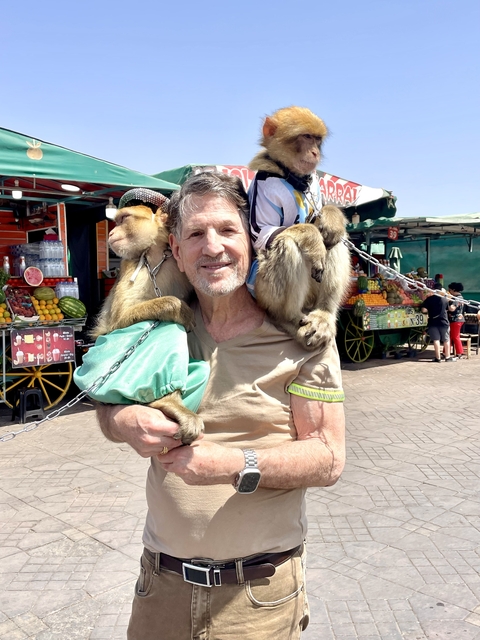 Man holding two monkeys, colorful market in background