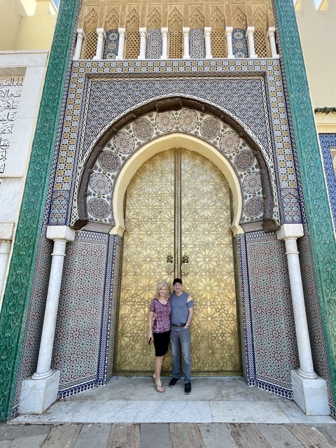       Two people standing in front of a large decorative gate
  