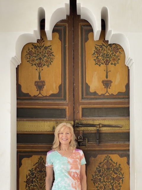       Person sitting in front of a decorative wooden door
  